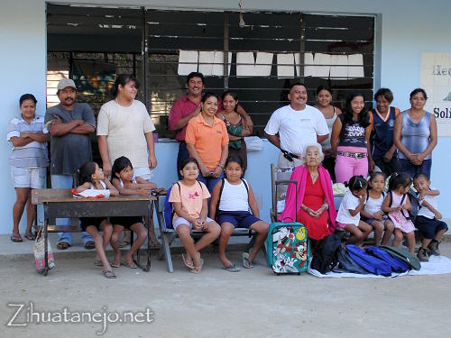 La maestra con los estudiantes y sus padres y do�a Cari con los donativos frente a la escuela de Mata de Sand�a